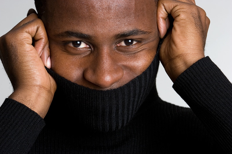 Man hiding smile with sweater